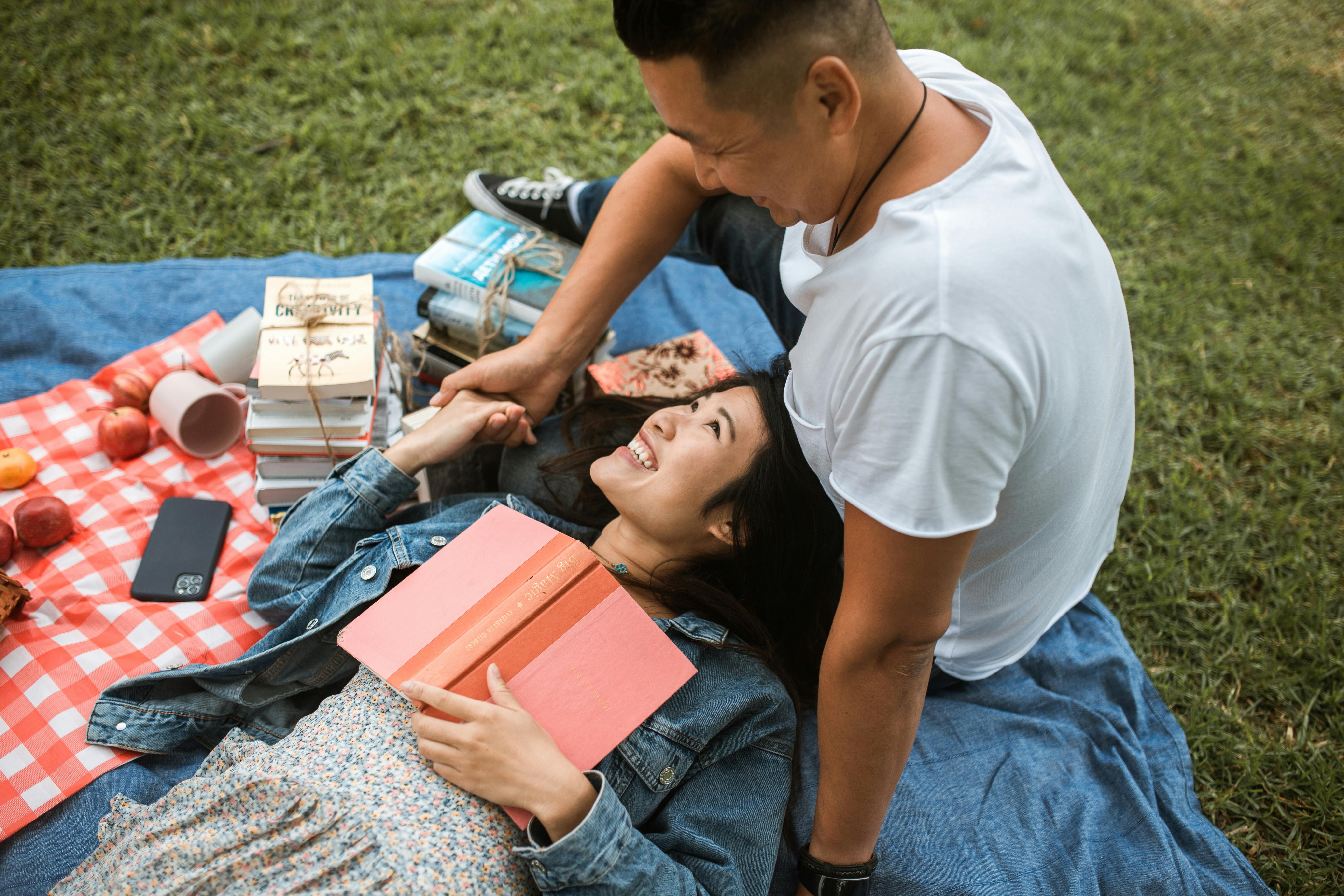 man and woman on picnic blanket reading books