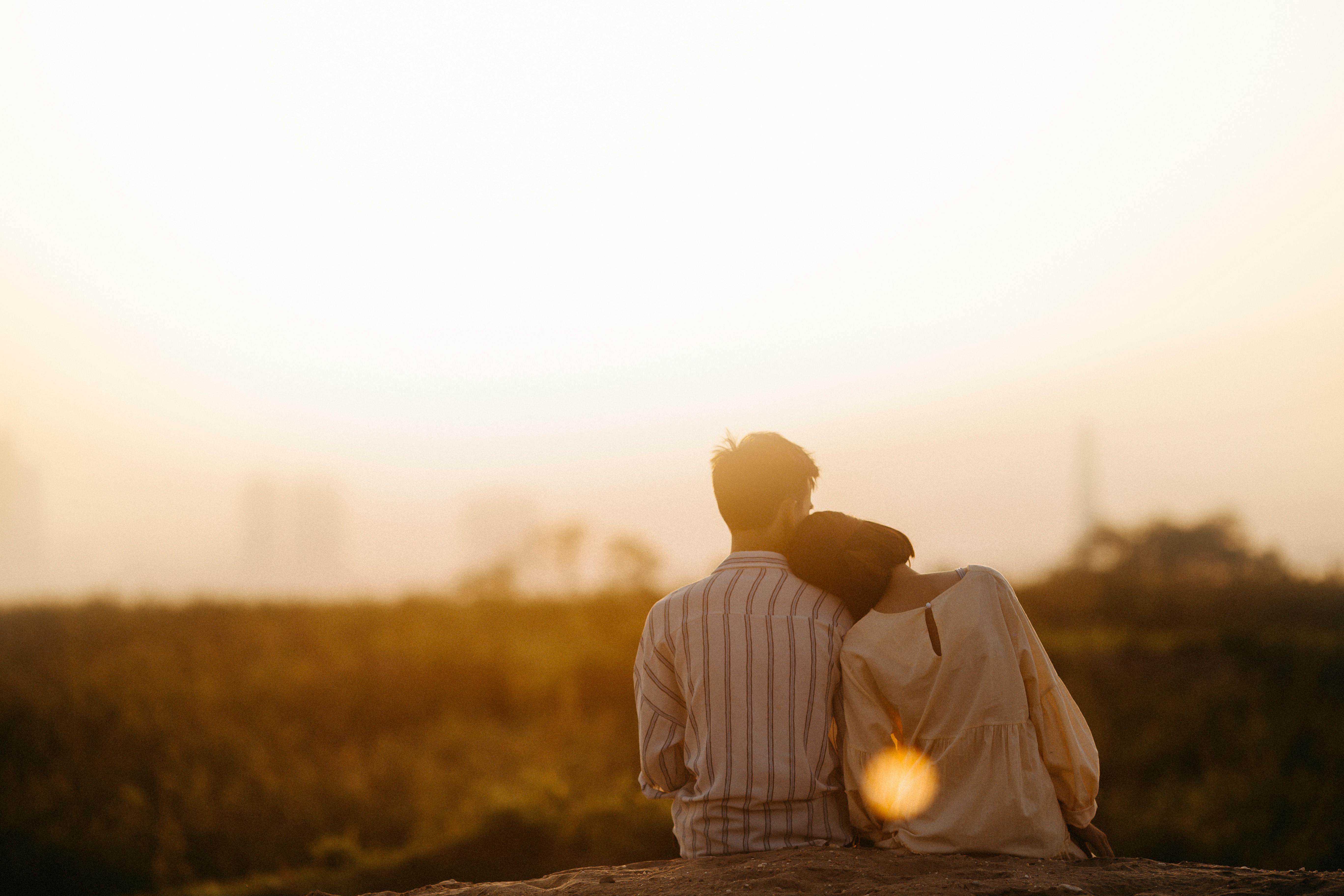 man and woman sitting at sunset