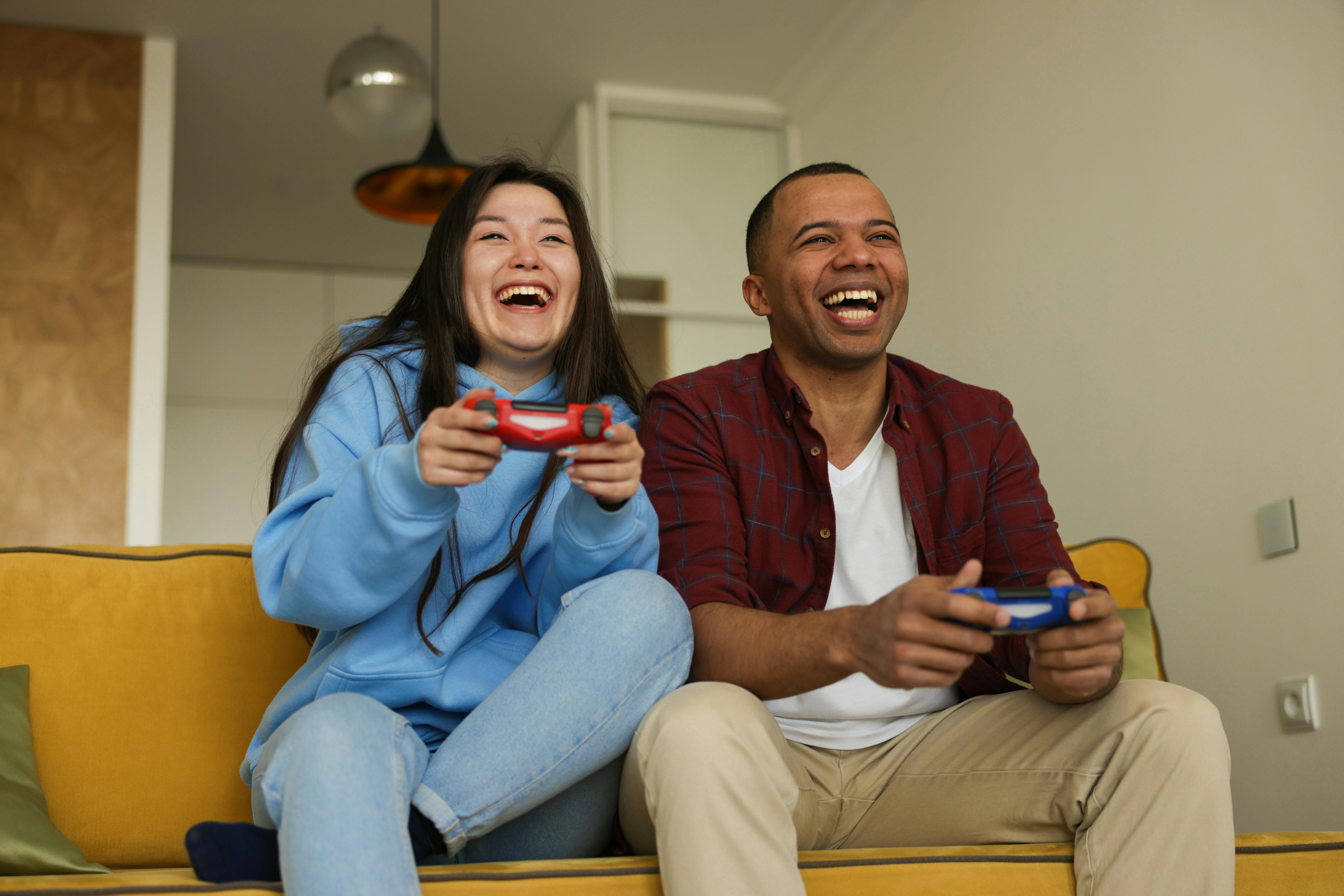man and woman playing video games on the couch