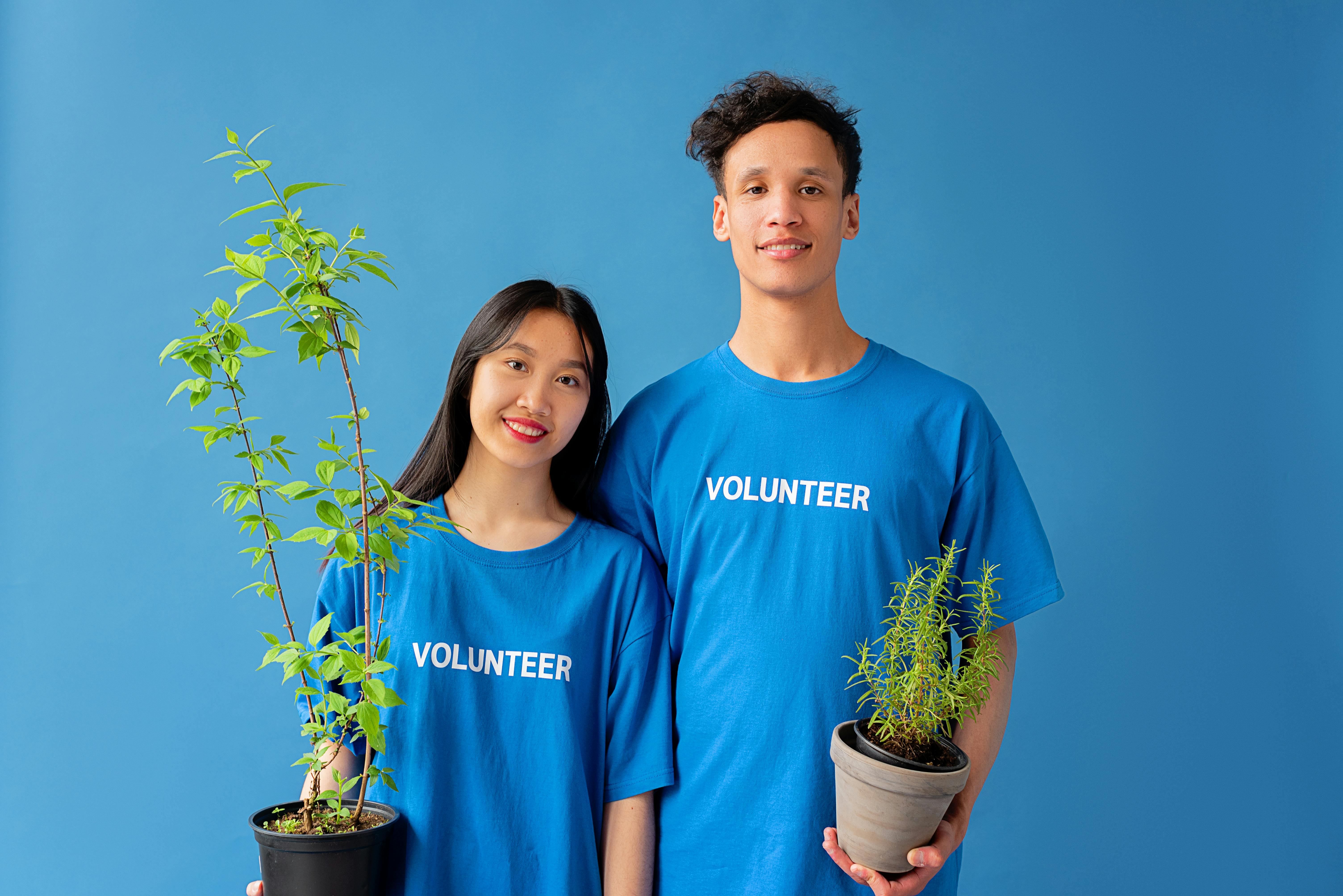 man and woman wearing volunteer tshirts and holding plants